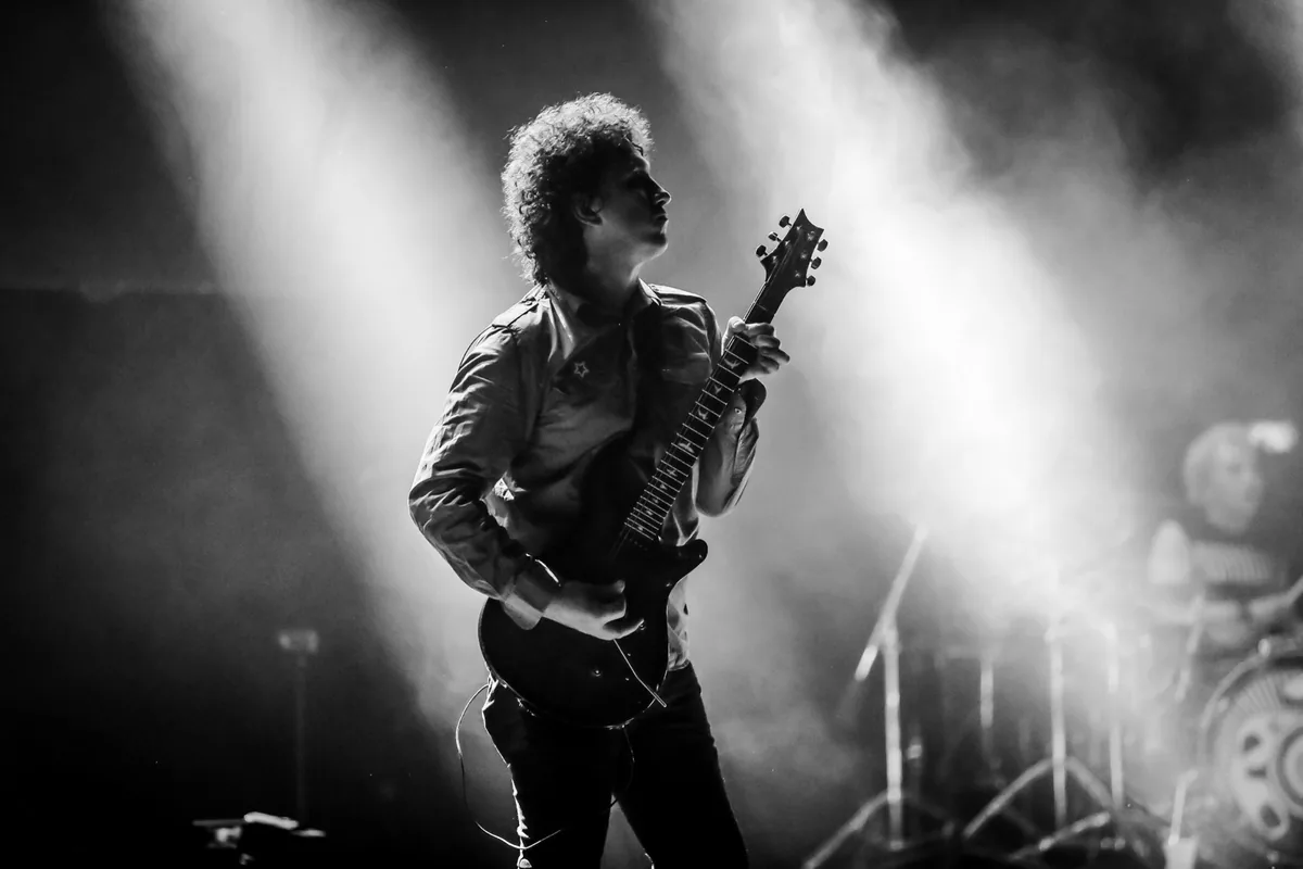 Felipe Reyes, fundador y vocalista de PROFUGOS, tocando guitarra en blanco y negro