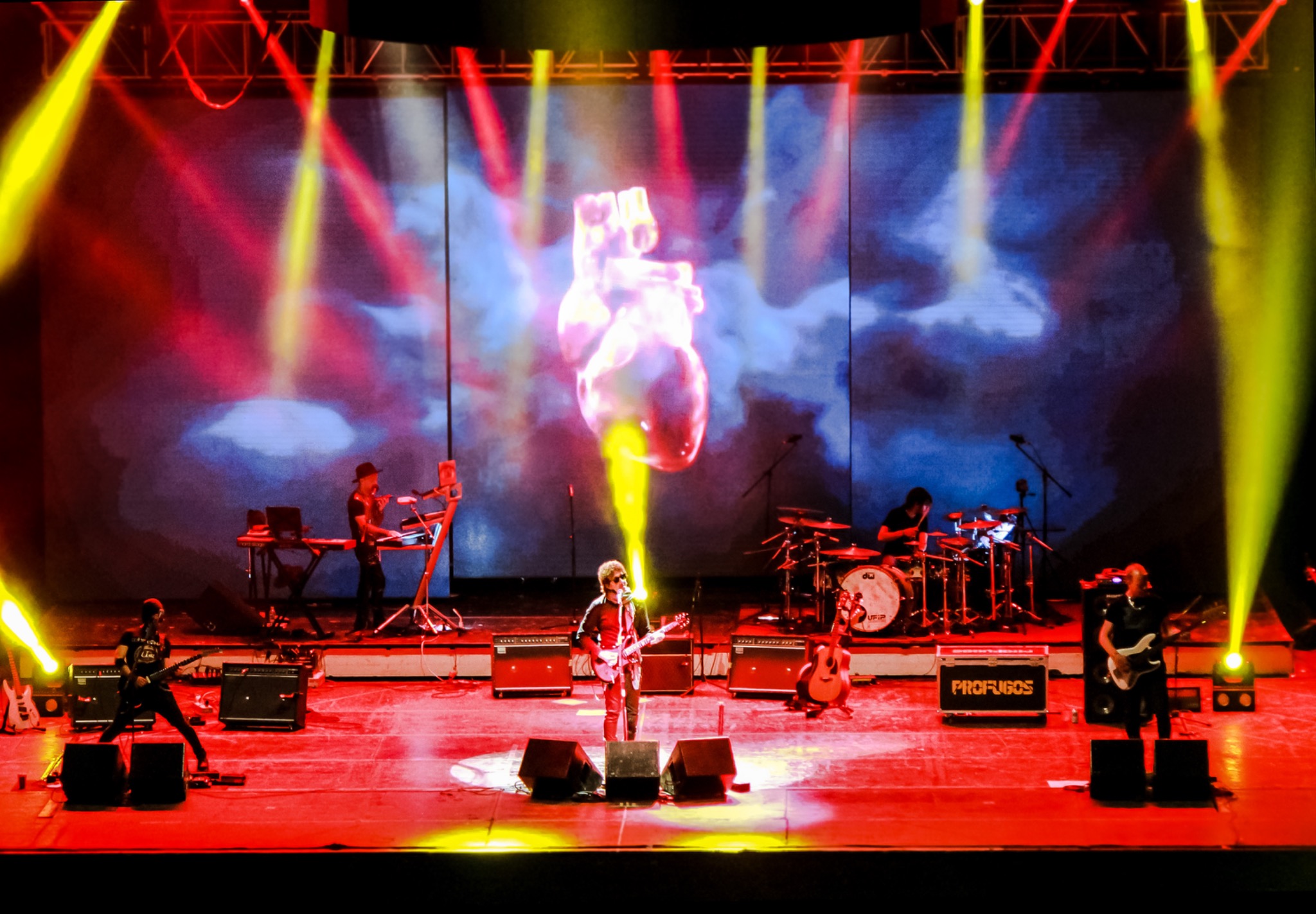 PROFUGOS en un gran escenario con visuales y luces rojas y amarillas